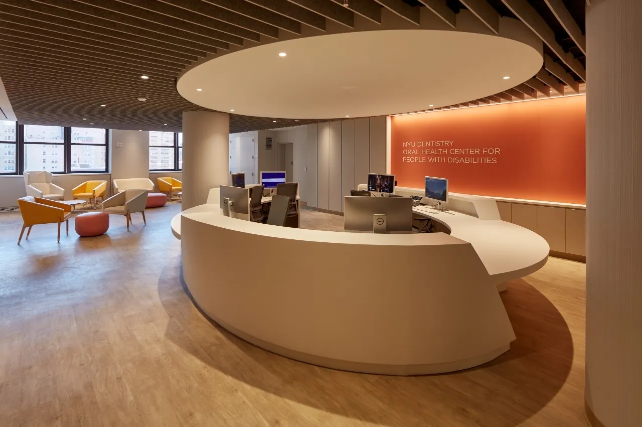Curved reception and waiting area of the NYU oral health clinic with warm orange accents