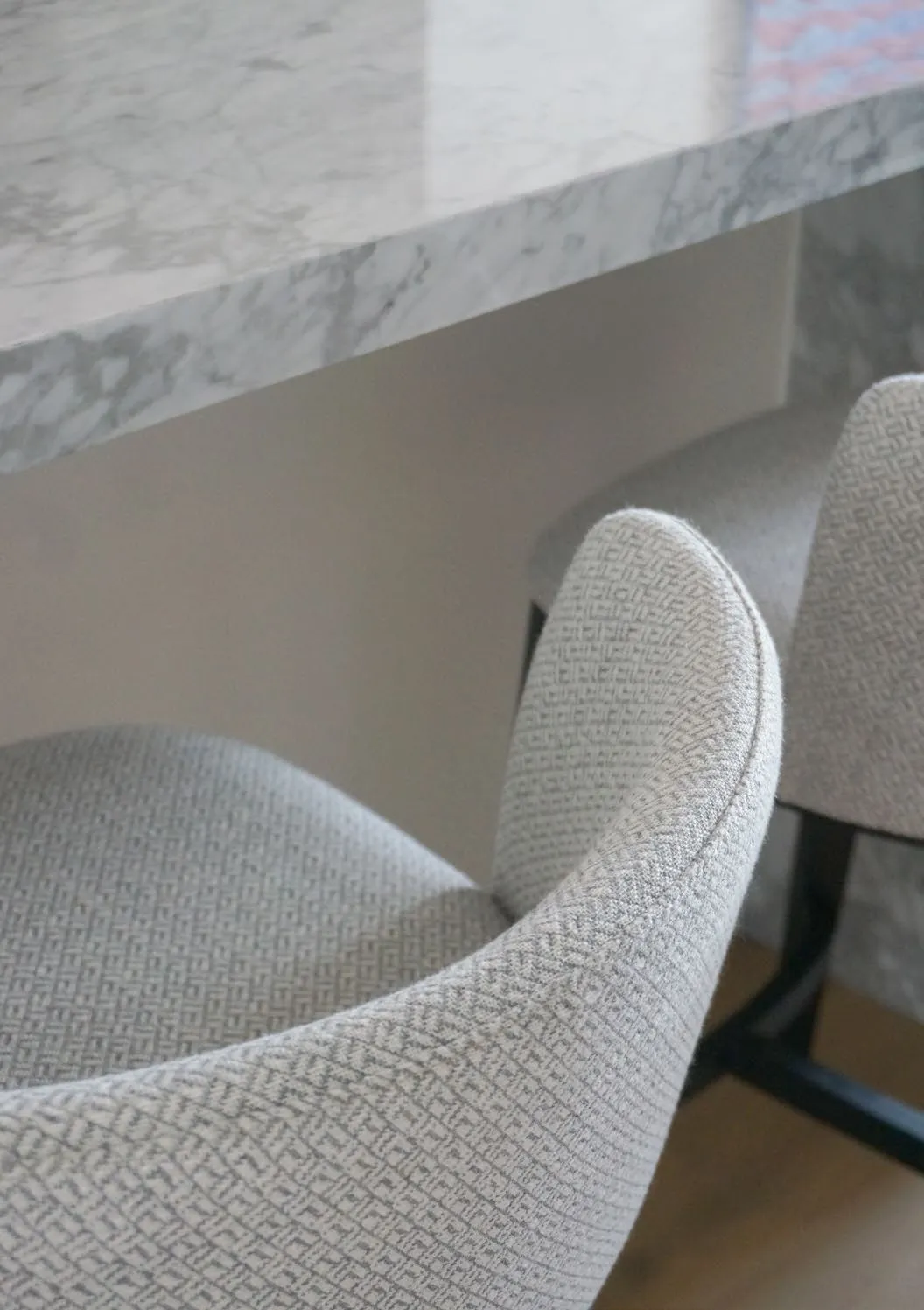 Grey-veined marble tabletop above woven wool dining chairs