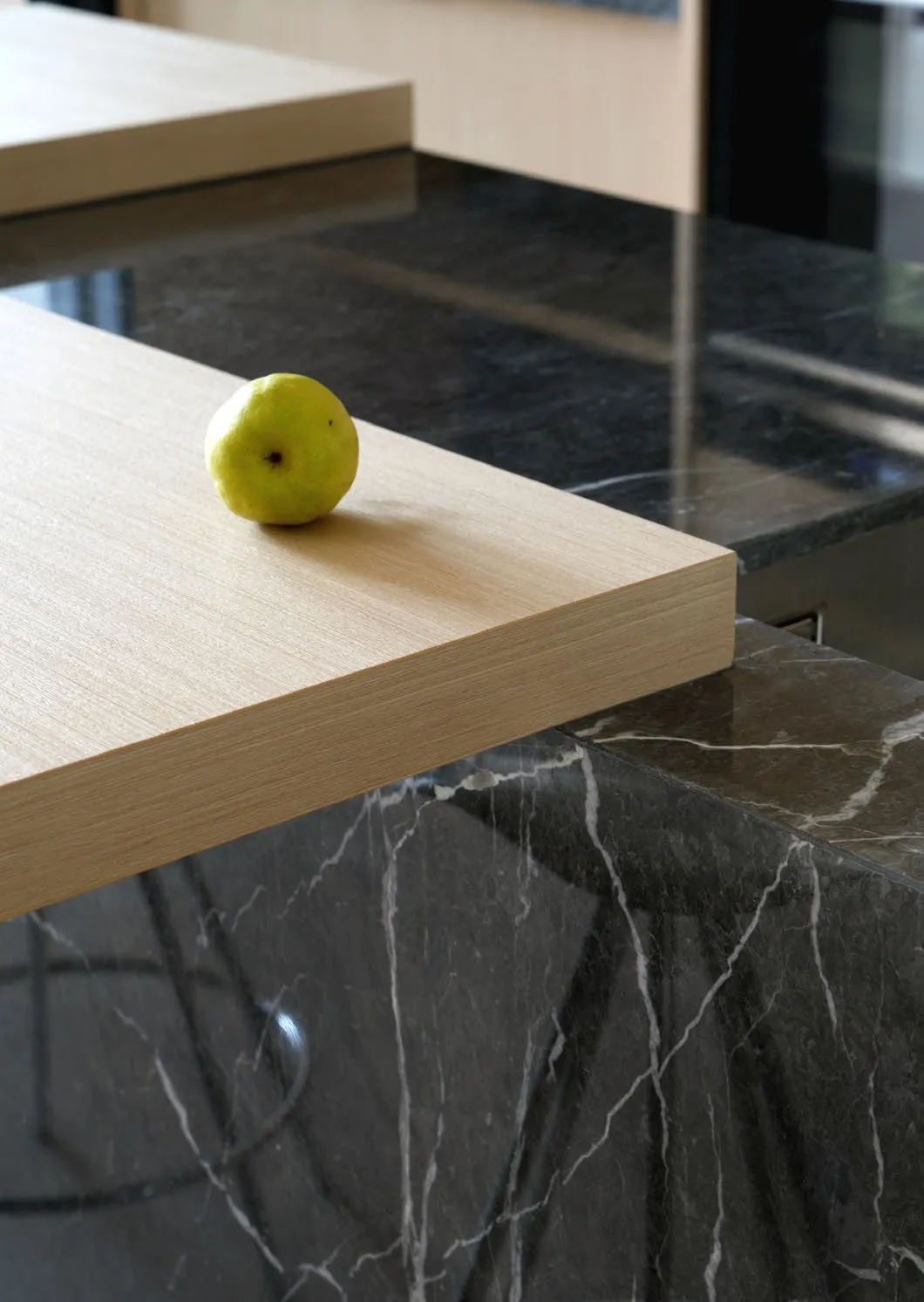 Pale oak counter meeting a dark veined stone island